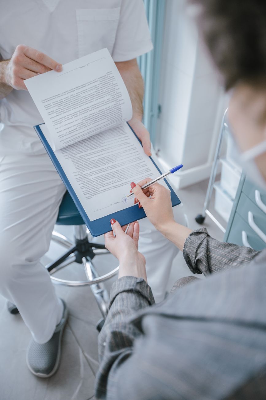 Patient signing a consent form during a healthcare consultation.