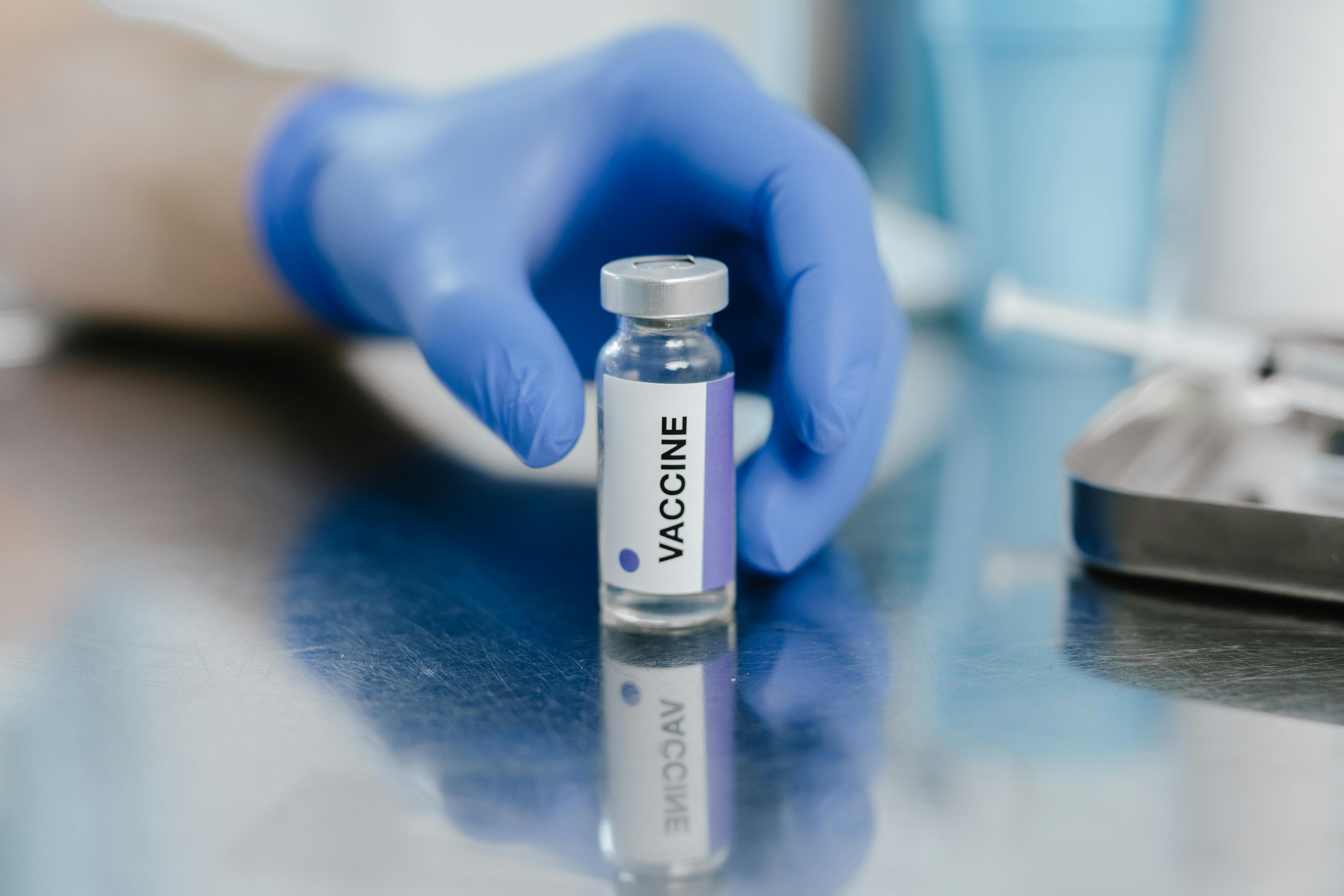 a person with blue gloves getting the vaccine vial