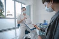 Woman in White Scrub Suit Holding White Paper