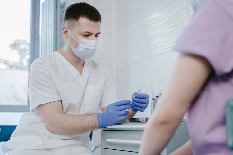 Doctor Sitting And Holding Syringe