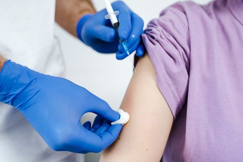 Free Close-up of a health professional administering a vaccine injection to a patient's arm. Stock Photo
