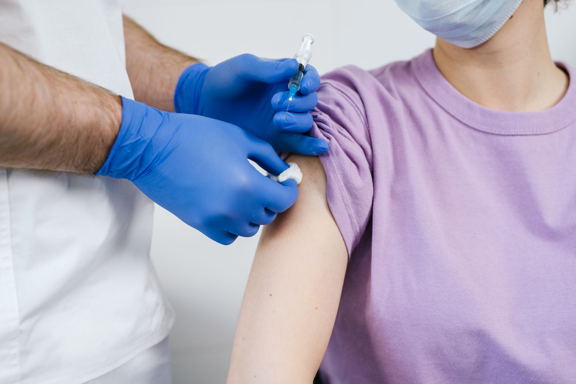 Close-up of a healthcare professional administering a vaccine to a patient in a clinical setting.