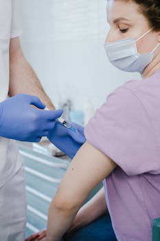 A medical professional in a clinic giving a vaccine injection to a patient.