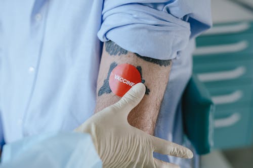 A Person in a Latex Gloves Sticking a Sticker on another Person 