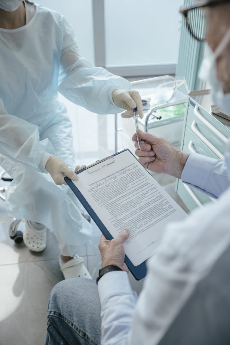 A Doctor Having A Patient Sign A Document