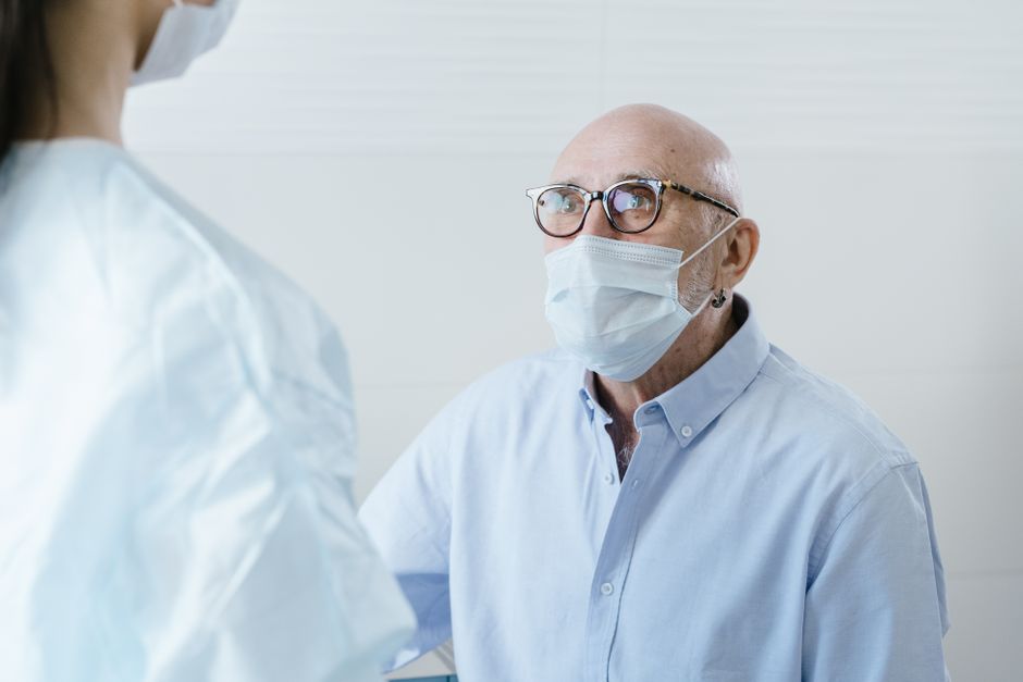 Elderly patient speaking with a doctor during a medical consultation — representing the mandatory pre-ceremony screening required before any bufo 5-MeO-DMT retreat