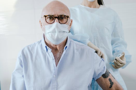 Portrait of a senior man receiving a vaccine injection by a healthcare worker wearing protective gear.