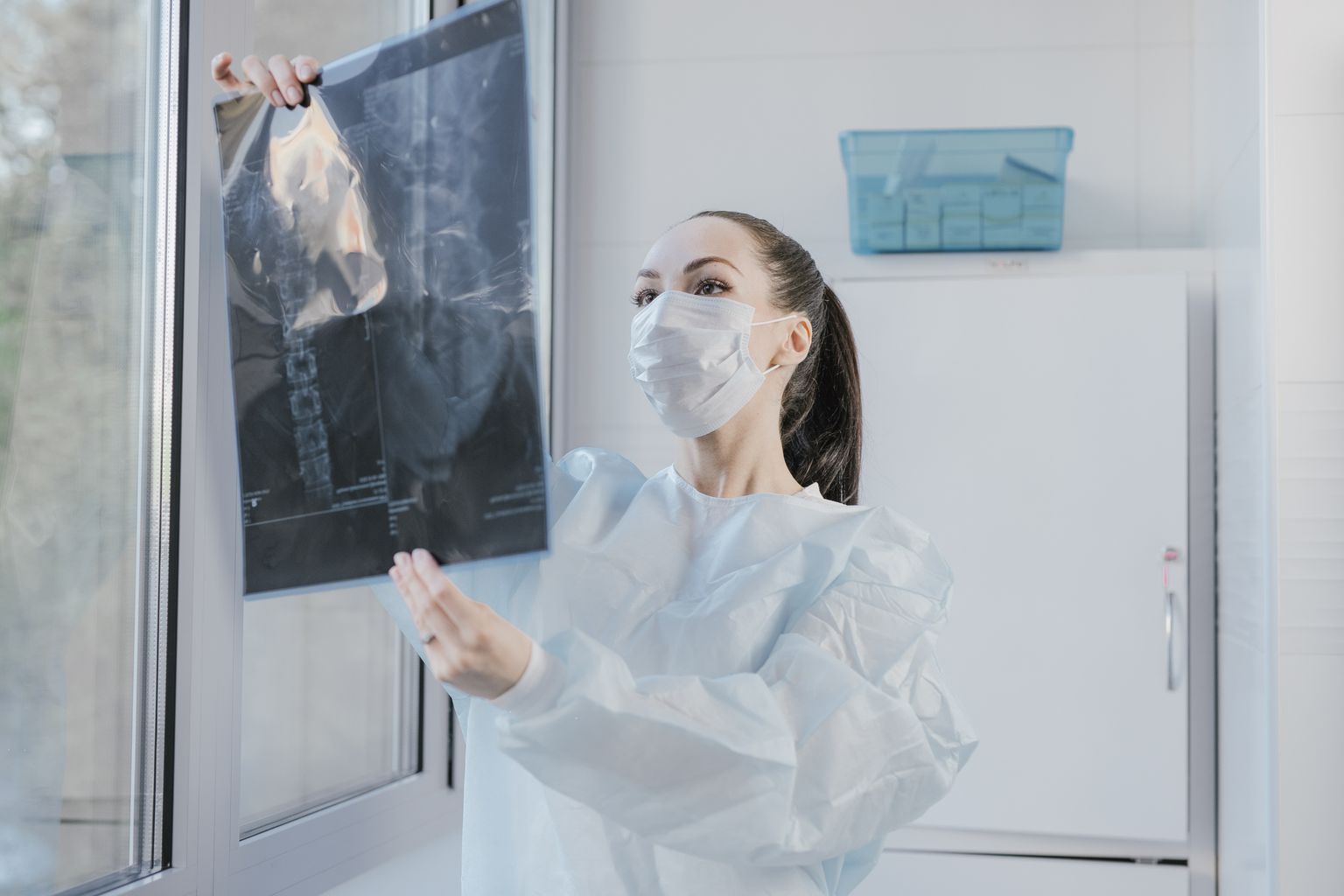 Healthcare professional examining an X-ray beside a window