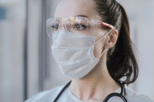 Free Close-up of a female medical professional wearing a mask and goggles for safety. Stock Photo