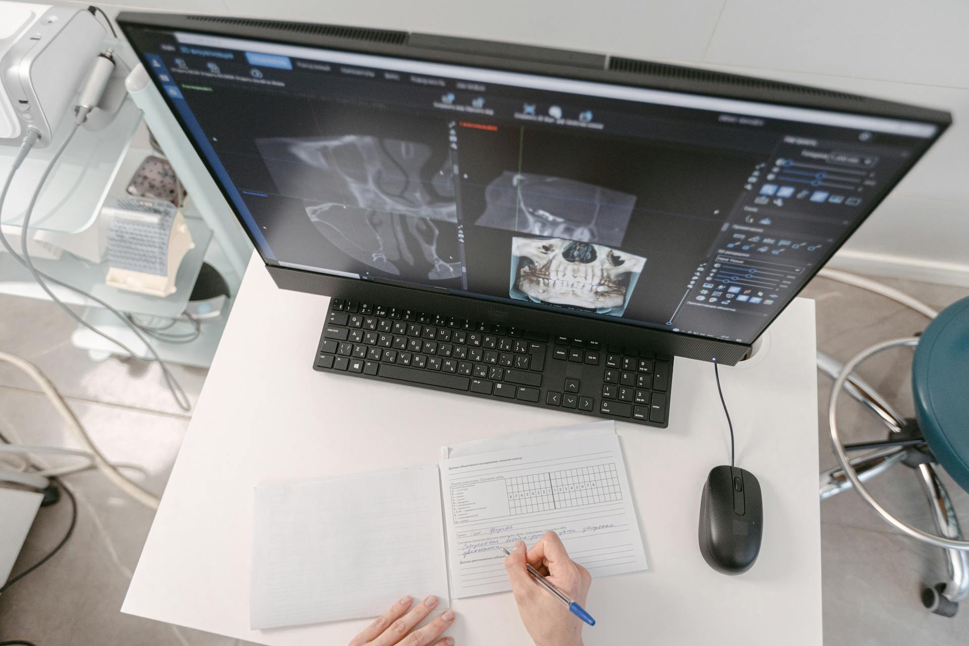 A Person Writing on a Document in front of a Desktop