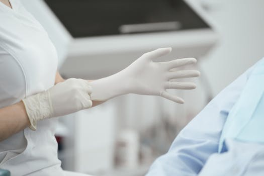 Close-up of a healthcare worker wearing latex gloves, preparing for a medical procedure.