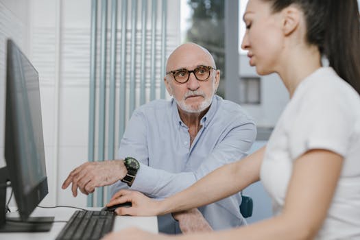Elderly man receiving consultation from a medical practitioner in a modern indoor setting.