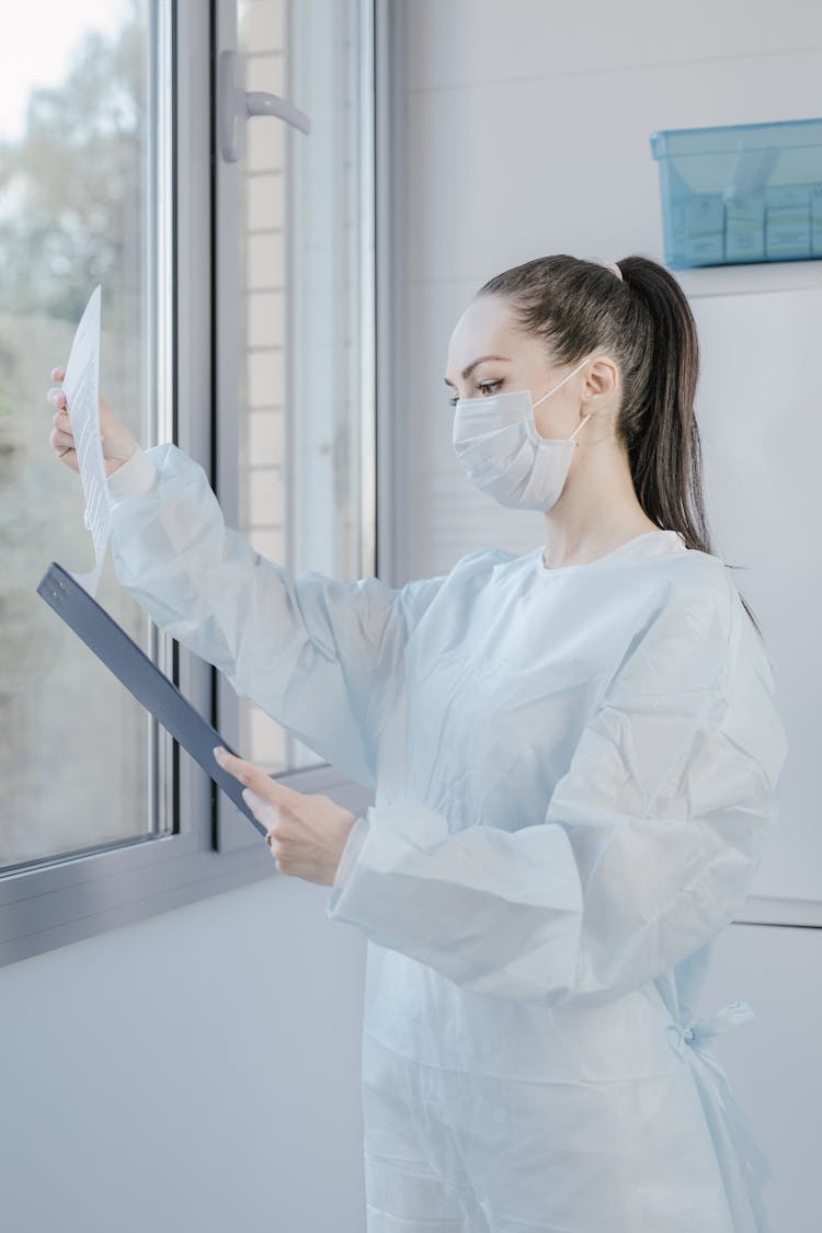 Woman Doctor Wearing Face Mask Holding A Clipboard