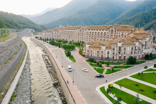 Stunning aerial view of a riverside resort amid lush mountains at day.