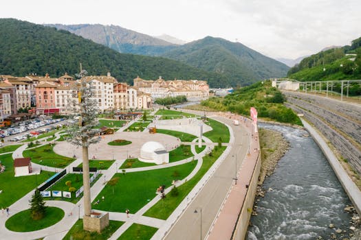 Aerial view of a beautiful riverside park nestled between mountains with vibrant greenery.
