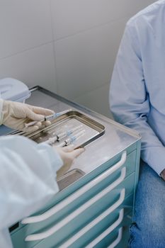 Doctor prepares syringes on a tray for a patient in a clinical setting.