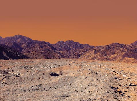 Stunning landscape of South Sinai's rocky desert under a vibrant orange sky.