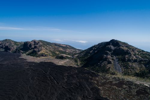 Free Aerial shot of mountainous terrain and volcanic landscape under a clear blue sky. Stock Photo