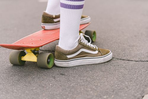 Free Detailed view of feet in sneakers on a skateboard on a concrete street. Stock Photo