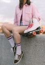Woman in Pink Blazer and Black Shorts Sitting on Concrete Pavement