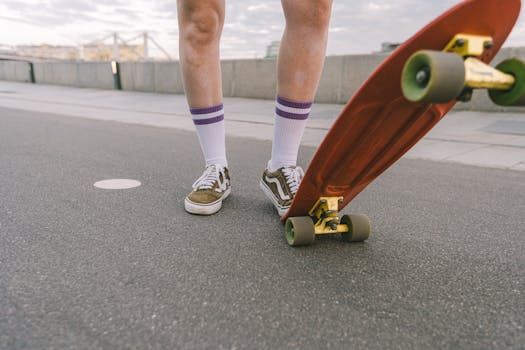 Legs with striped socks and skateboard standing on a city sidewalk.