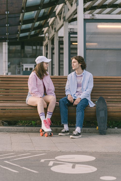 Free Man and Woman Talking while Sitting on a Wooden Bench Stock Photo