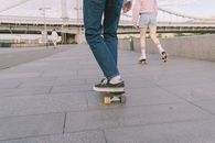 Woman in Blue Denim Jeans and White Sneakers Standing on Gray Concrete Floor