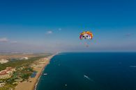 People Riding on Yellow and Red Parachute over Blue Sea