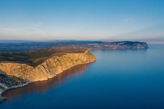 A stunning aerial view of coastal cliffs and the sea at sunset, showcasing natural beauty.