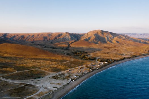 A stunning aerial view of a coastal mountain range along a serene beach at sunset.