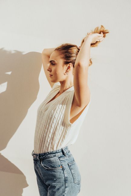 Young woman in casual outfit striking a stylish pose under indoor lighting.
