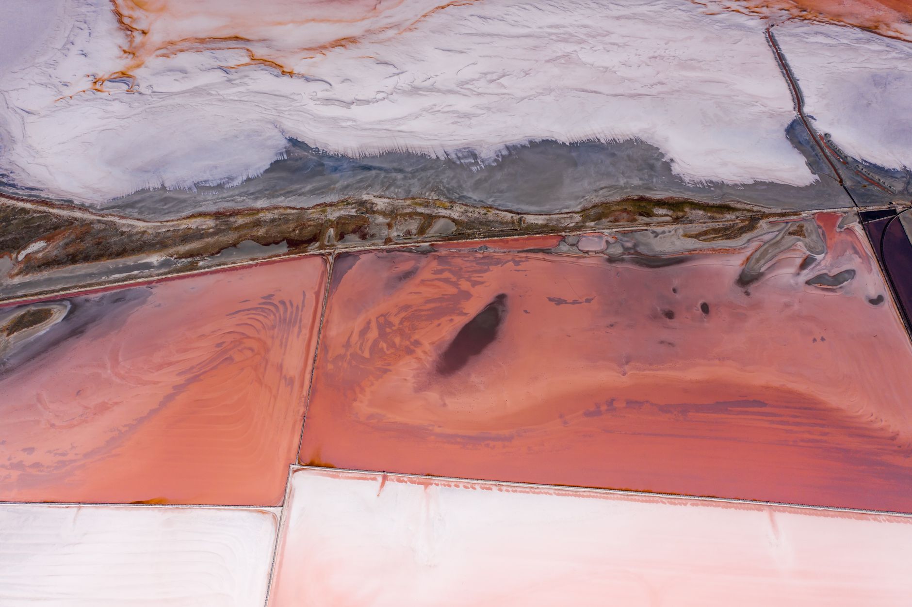Aerial photograph capturing the striking hues and patterns of salt ponds, with rich pink and white tones.