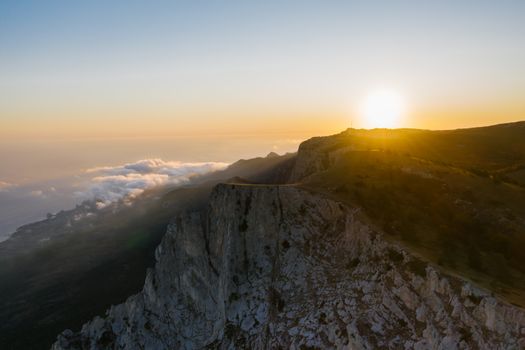 A breathtaking aerial view of a scenic cliff with the sun setting in the background.