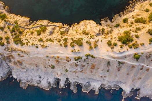 A breathtaking aerial view of a coastal cliffside path with the sea below.
