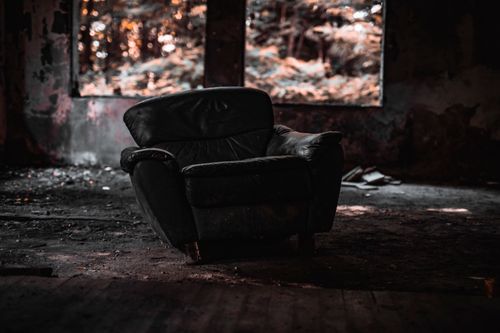 Free Old armchair in a weathered, abandoned room with a forest view outside. Stock Photo