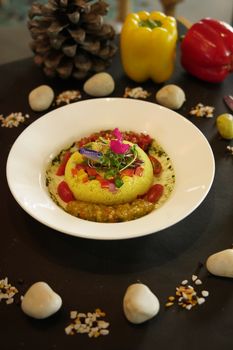 A beautifully presented gourmet dish with yellow and red bell peppers accentuated by edible flowers.