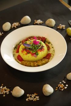 Elegant gourmet dish featuring couscous, edible flowers, and vibrant garnish on a stylish plate.