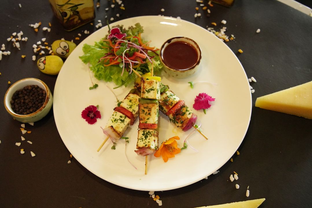 Healthy Summer Salads: 8 Protein-Rich Recipes for Indian Kitchens 3 Grilled paneer skewers on a white plate with fresh salad greens and dipping sauce — halloumi-style grilled paneer technique for a protein-rich salad.