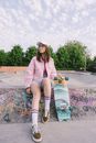 A Woman in a Pink Jacket Holding Her Skateboard