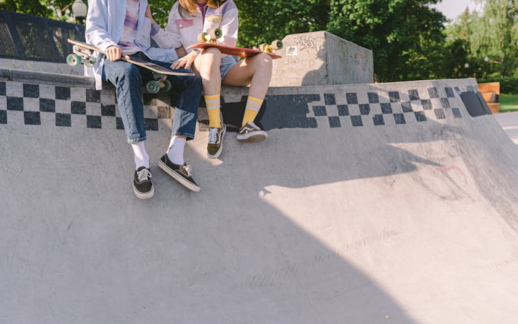 A Couple Sitting On A Skate Ramp