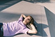 Woman in Blue Sleeveless Dress Lying on Gray Concrete Floor
