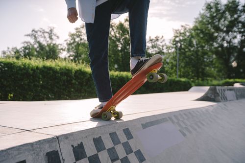 Free Close-up of a skateboarder performing a trick in a sunlit skate park. Stock Photo