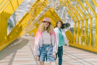 Woman in White Long Sleeve Shirt and Blue Denim Shorts Standing on Wooden Bridge