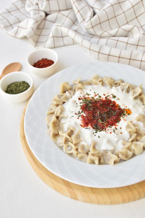 Free Delicious Turkish manti dumplings topped with yogurt and spices on a white plate. Stock Photo
