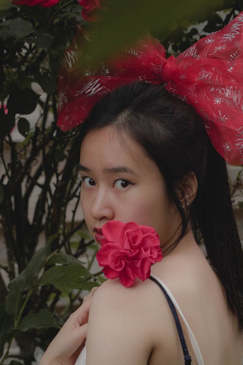 Portrait of Woman Holding Flower with Big Pink Bow on her Head