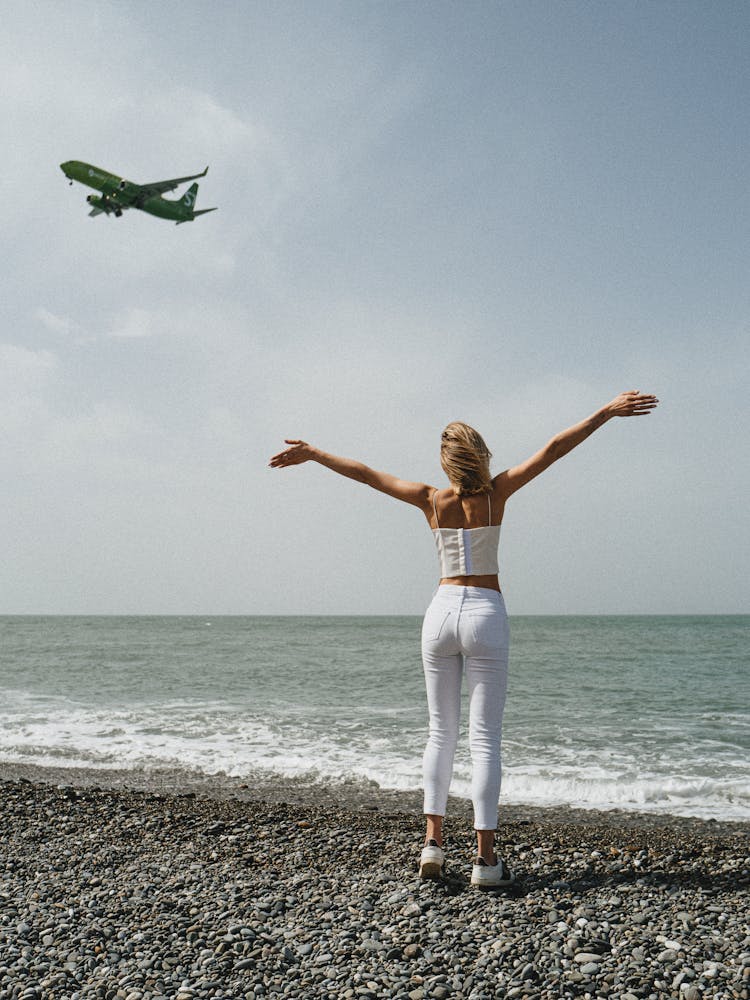 Woman Looking At A Flying Airplane