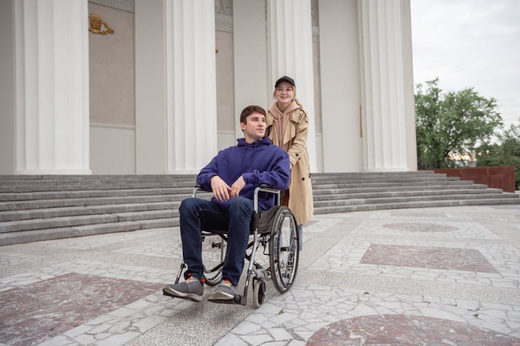 Woman Pushing A Man Sitting On A Wheelchair