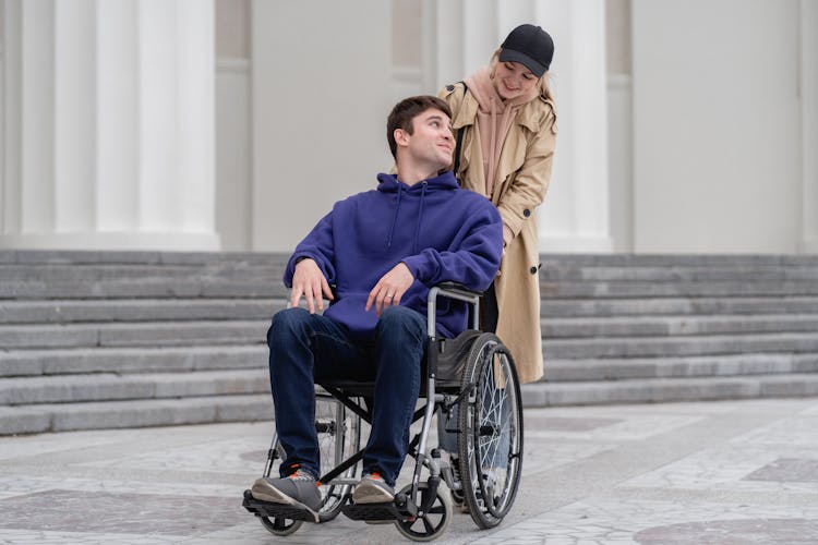 Woman Pushing A Man Sitting On A Wheelchair