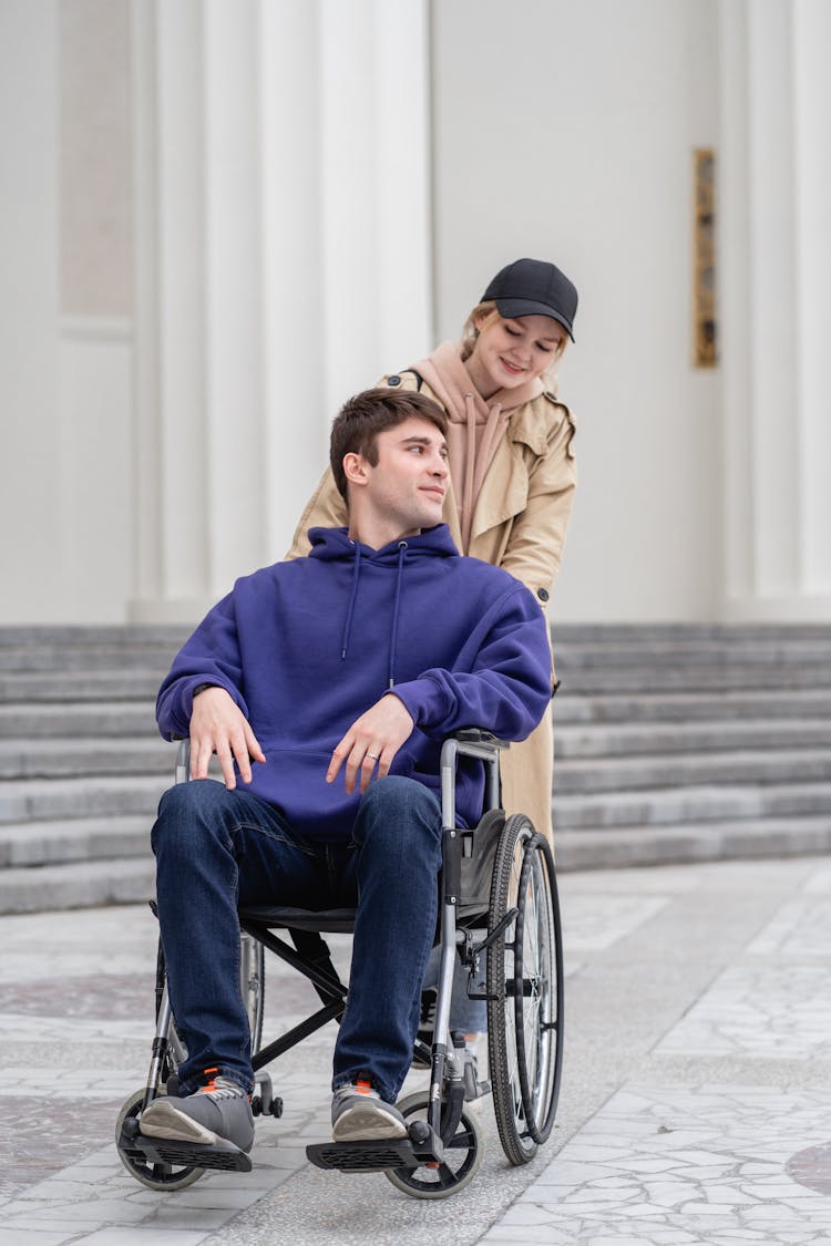 Woman Pushing A Man Sitting On A Wheelchair