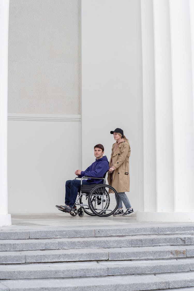 A Woman Pushing A Wheelchair With Man